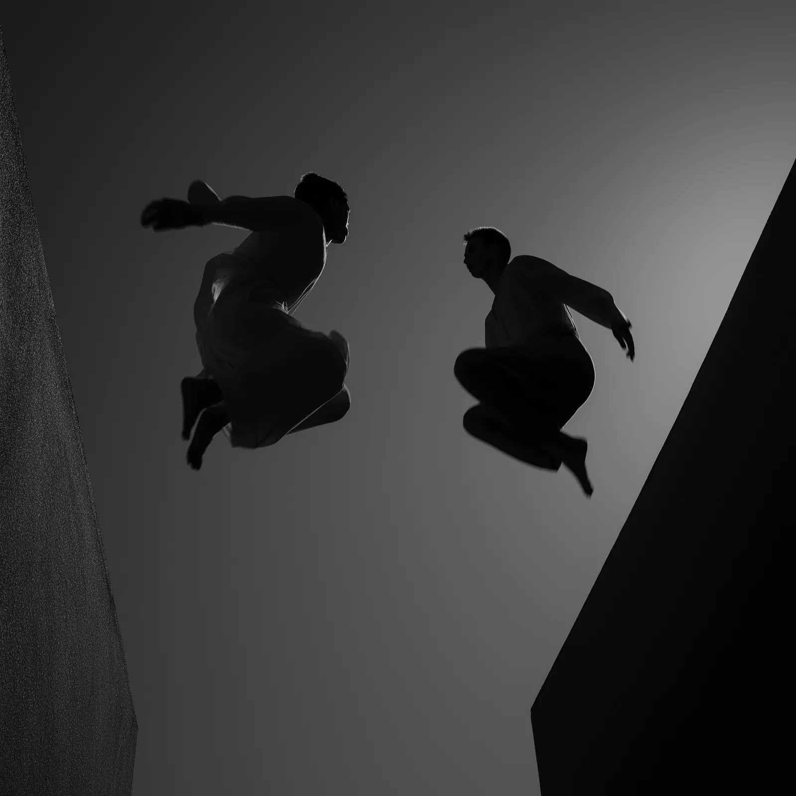 Two people jump between dark walls